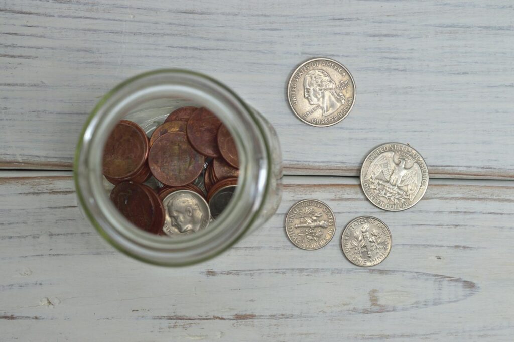 Top view of a jar filled with coins placed on a wooden table, depicting savings.